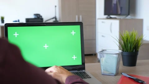 Revealing shot of man working on the computer with a chroma green screen mock up Stock Footage 95671100