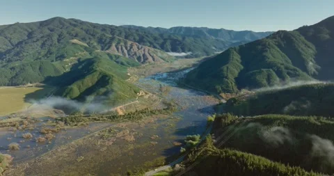 Reverse aerial flight of Te Paranui wetland ecosystem within wild, rugged Stock Footage 257641581