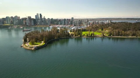 Reverse aerial out of stanley park vancouver with view of park and city skyline Stock Footage 239076157