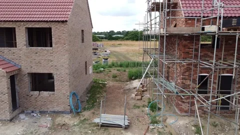 Reverse aerial view through two new build houses showing the side and Vídeos de archivo 202556611