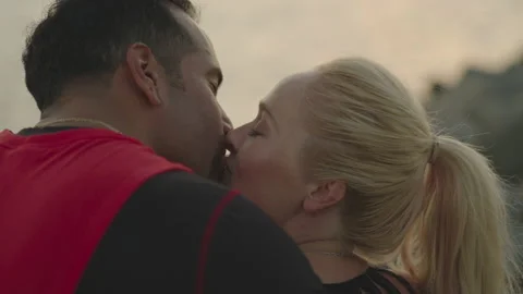 Reverse close-up of attractive couple sharing romantic kiss at ocean sunset Stock Footage 136020262