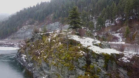 Reverse curve shot around large rock formation in river with moss and snow on Stock Footage 125278019