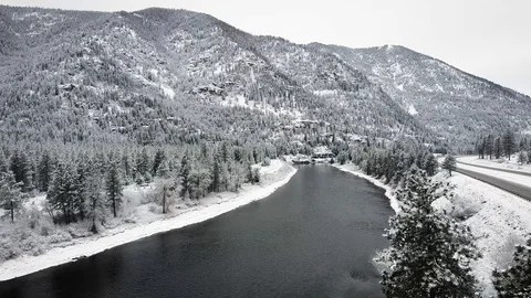 Reverse dolly shot away from calm river surrounded by snow and trees in Montana Stock Footage 125491254