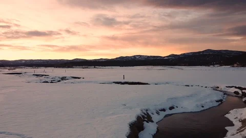 Reverse dolly shot of epic sunrise over snow covered field with winding creek Stock Footage 125384488