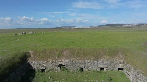 Reverse drone flight revealing 18th-century pig farming stone structure Stock Footage 308900399