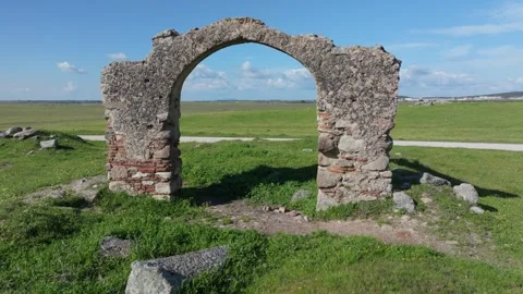 Reverse drone flight through ancient brick arch in green field Stock Footage 308949304