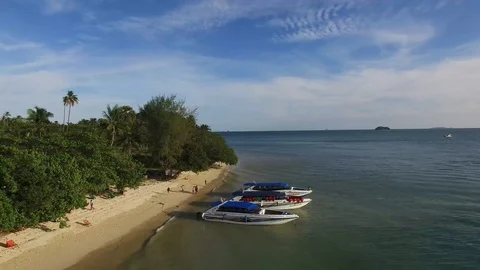 Reverse drone pull back along island beach coast passed boats Stock Footage 97248643