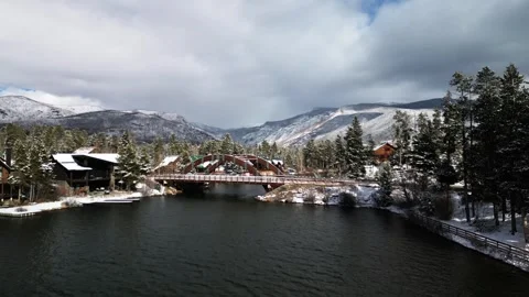 Reverse drone shot snowy mountains with bridge over lake Stock Footage 255682460