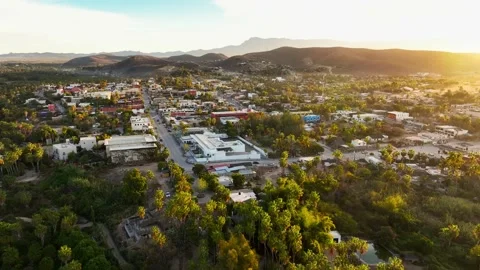Reverse flight out of small Mexican town backed up to the mountains at sunrise Stock Footage 236741263
