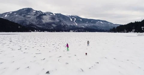 Reverse Fly Over Of Two Women And Dog Skating Outdoors On A Frozen Lake In The M Video stock 83800687