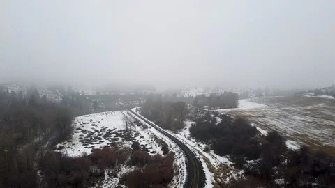 Reverse long tracking shot over a snow covered valley being cut through by a Stock Footage 124616318