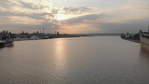 Reverse move over industrial harbor at sunset passing several large boats Video stock 112581264