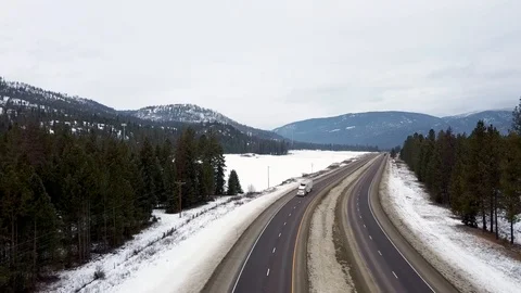 Reverse overhead shot with large freight truck passing through with snow, tre Stock Footage 124713902