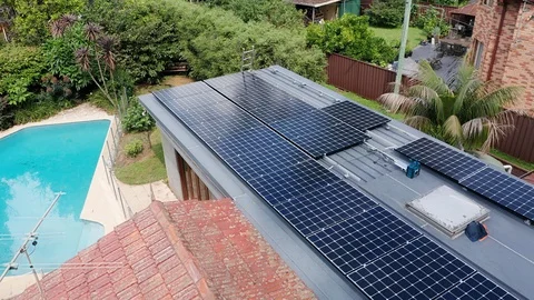 A reverse passing aerial shot of solar panel installation by trades men Stock Footage 130108742