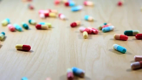 Reverse Pills Capsules failling down the wood plate Stock Footage 77881807