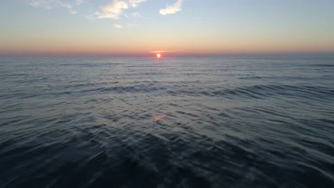 Reverse Pullback Shot of the Setting Sun Above the Ocean Waves Stock Footage 136482681