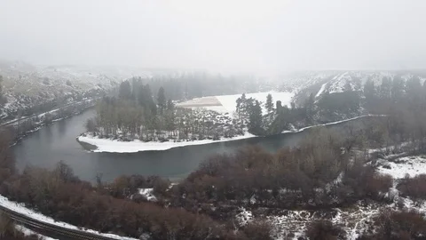 Reverse side tracking shot across river and train track in a snow covered val Stock Footage 124616324