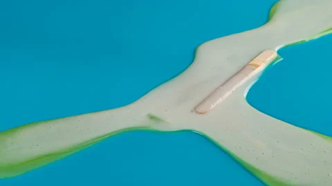 Reverse side view studio shoot yellow popsicle melting on blue timelapse Stock Footage 92971217