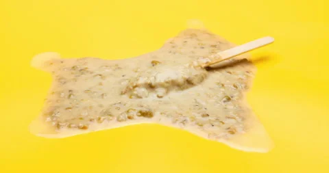 Reverse of studio shoot of green bean popsicle melting time lapse on yellow Stock Footage 94239037