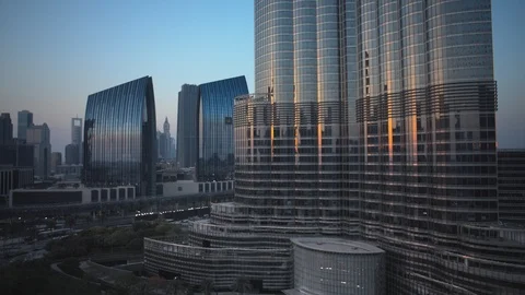 Reverse track back slow pan left at base of Burj Khalifa at 60m, sunset. Stock Footage 98952103