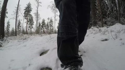 Reverse tracking shot of backpackers feet as he's walking in snow Stock Footage 145944676