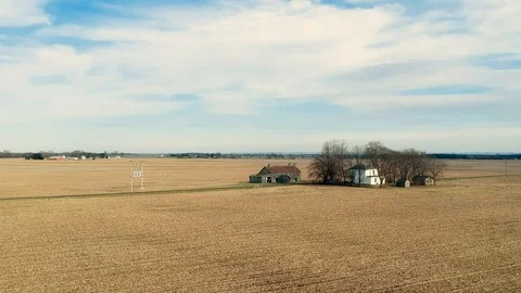 Reverse tracking shot of farmhouse and barn in middle of large cornfield Video stock 100416558