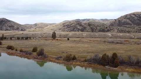 Reverse tracking shot over wide green river away from vast rolling hills Stock Footage 125054160
