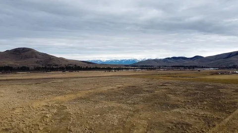 Reverse tracking shot wide open grass field with rolling hills and snow cappe Stock Footage 125050658