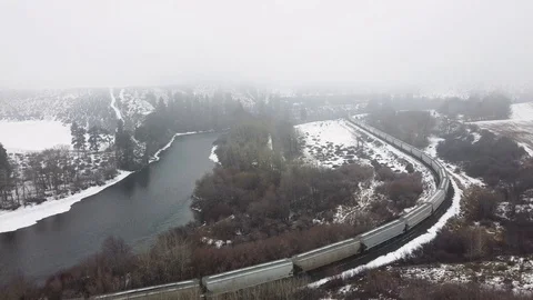 Reverse tracking show over a train passing through snow covered valley Stock Footage 124616211
