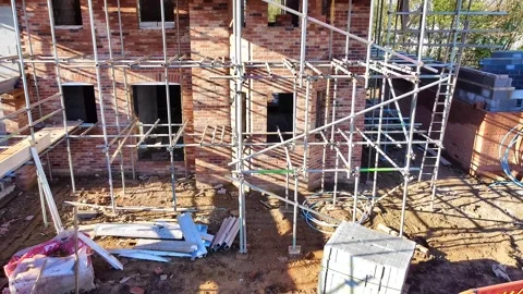 Reversing view of a scaffolded house under construction Stock Footage 339614516
