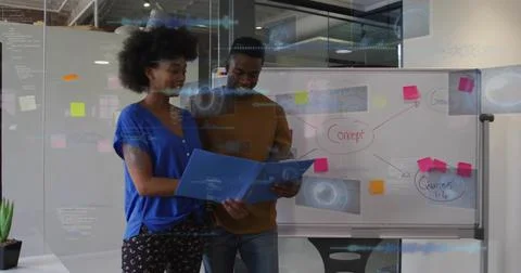 Reviewing blue folder, pair in blue blouse and brown sweater discussing Stock Photos