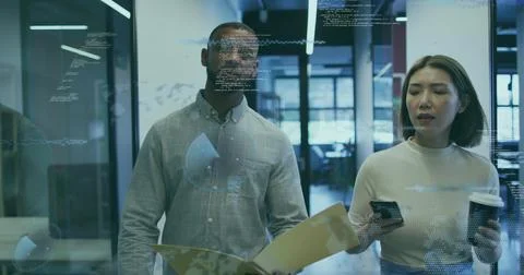 Reviewing code, pair in office attire studying glass wall, holding folder, Stock Photos