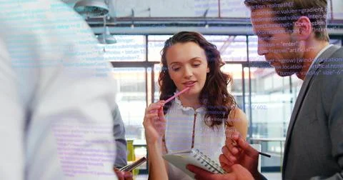 Reviewing code projected on glass by team in office in business attire with Foto stock