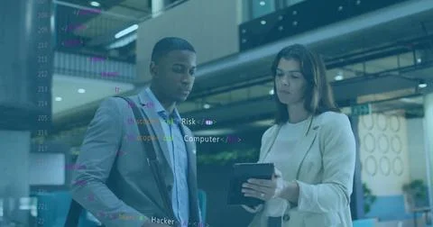 Reviewing code on tablet, professionals in blazers carrying shoulder bag in 库存照片