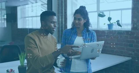 Reviewing data visualization, two coworkers standing by desk at office, with Stock Photos