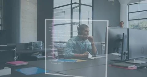 Reviewing developer wearing headset and light shirt debugging code on large 库存照片