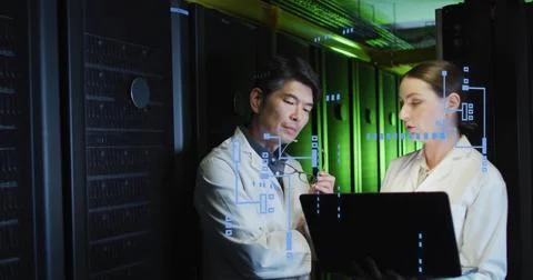 Reviewing laptop diagnostics, two engineers in white lab coats with eyeglasses Stock Photos