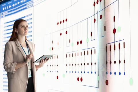 Reviewing PCB layout, tablet and female engineer looking at large digital screen Stock Photos