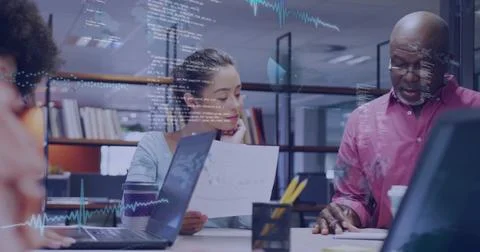 Reviewing printed reports, three professionals analyzing charts in library Stock Photos