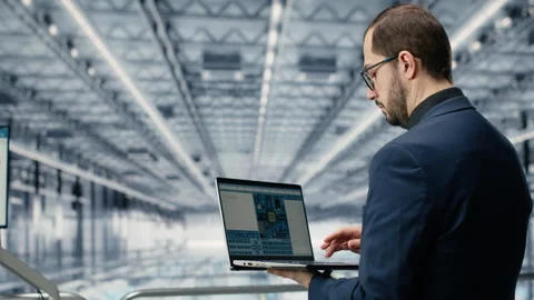 Reviewing schematics, laptop and engineer man in semiconductors smart factory Stock Footage 333384266