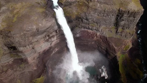 Revolving drone shot looking down at a tall waterfall. Clouds move in. 库存影片 158059213