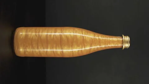 Rheoscopic liquid inside glass bottle on black background. Gold. Vertical video Video stock 252033531
