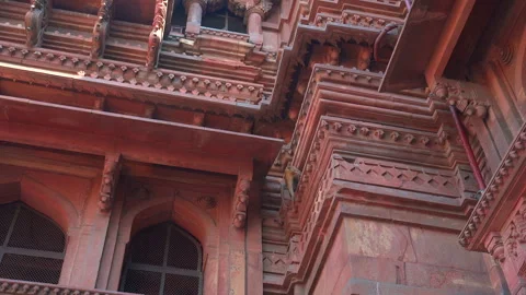 Rhesus macaque monkey climbing ornate red sandstone temple facade 库存影片 341325234