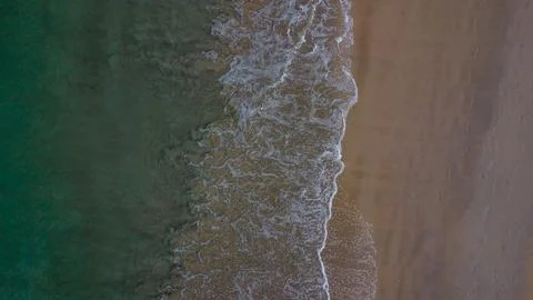Rhythmic dance of foamy white waves as they meet the serene shoreline Stock Photos
