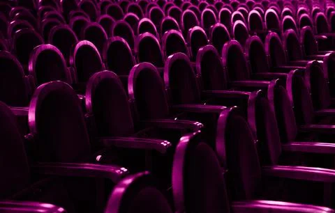 Rhythmic pattern of empty purple velvet theater seats in dark hall 스톡 사진