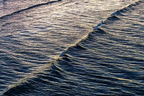 Rhythmic sea waves in evening time. Water surface texture with highlights. Stock-Fotos