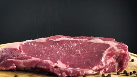Rib eye beef steak sprinkling with salt in slow motion footage clip Stock Footage 147174325