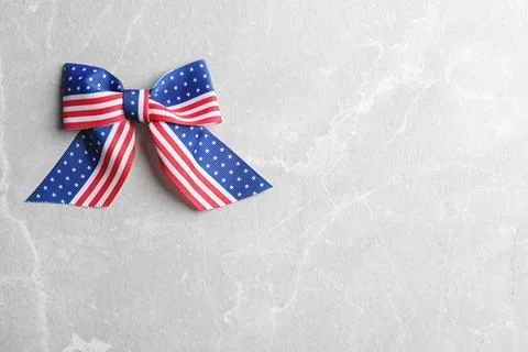 Ribbon bow with American flag pattern on light background, top view with spac Stock Photos