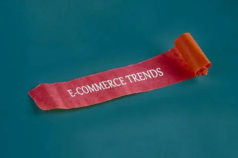 A ribbon with the text e-commerce trends rests on a solid teal background, sy Stock Photos