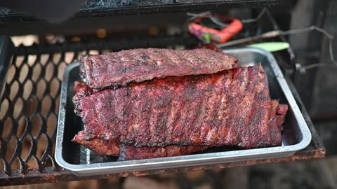 Ribs are placed on a tray during the cooking process on a grill. The outdoor Stockbeeldmateriaal 337101273